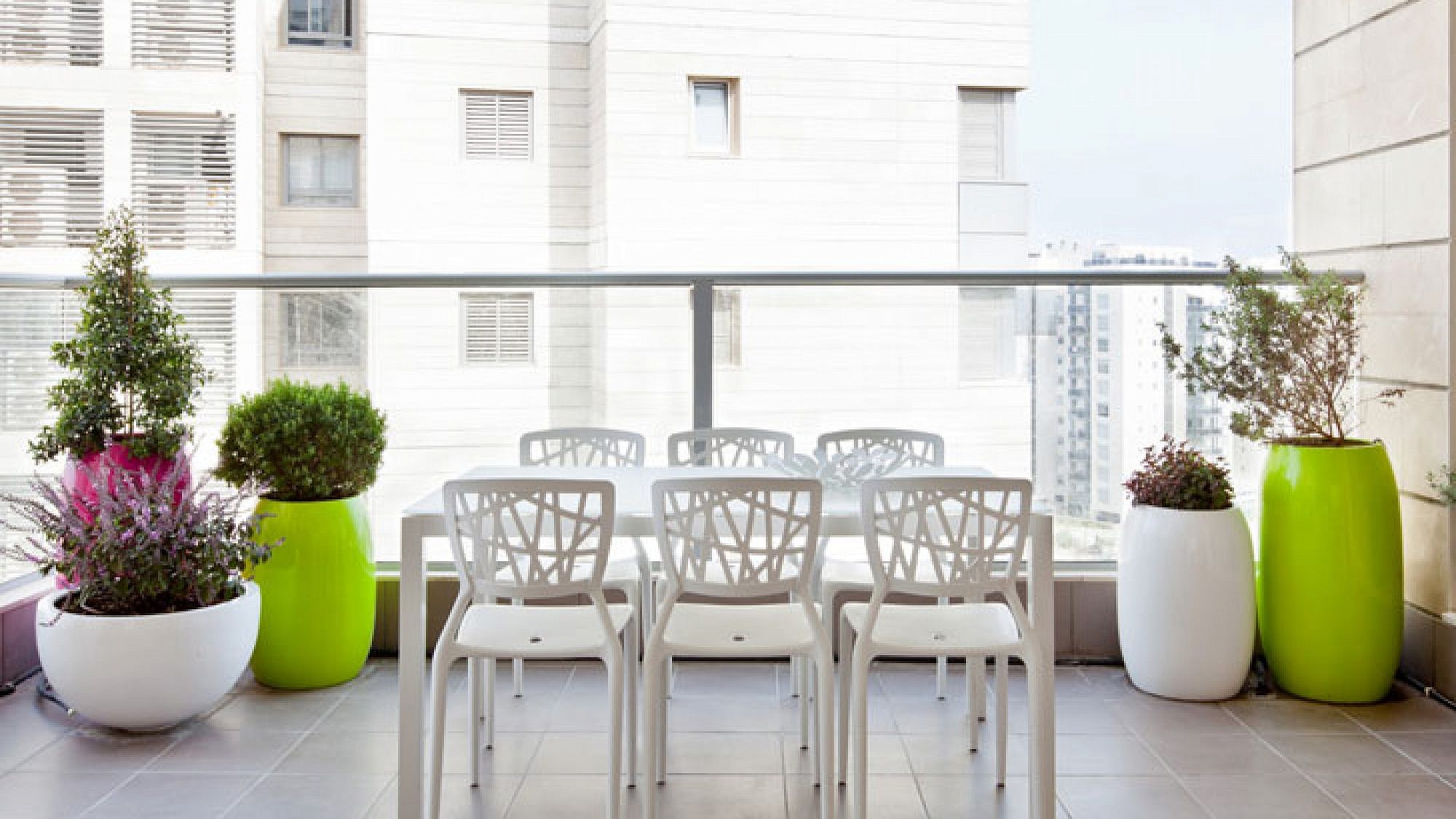 במרפסת שולבו כדים צבעוניים גדולים לצד מערכת ישיבה לבנה מאיי. די.דיזיין | צלם: בועז לביא