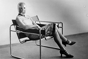 אריך קונסמולר, אשה יושבת על כיסא וסילי בעיצוב מרסל ברוייר, ועל פניה מסכה של אוסקר שלמר, 1926 בקירוב | ארכיון באוהאוס, ברלין