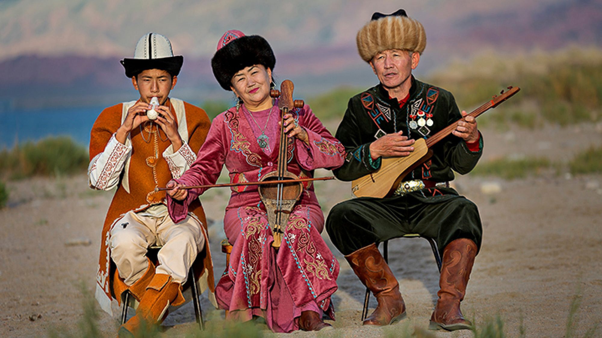 נגנים בלבוש מסורתי על יד אגם איסיק-קול בקירגיזסטן | צילום: Shutterstock