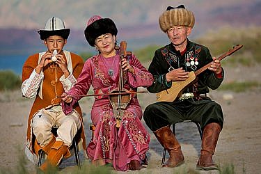 נגנים בלבוש מסורתי על יד אגם איסיק-קול בקירגיזסטן | צילום: Shutterstock