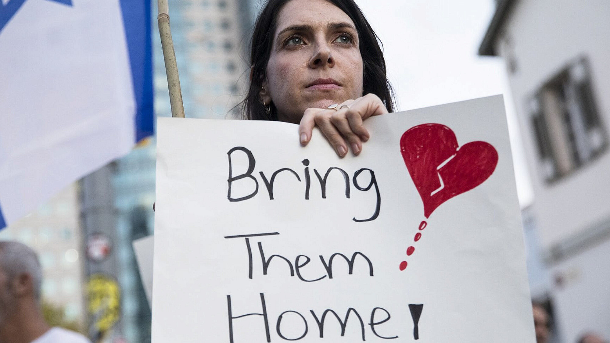 אישה מחזיקה שלט במחאה להחזרת החטופים | צילום:  Amir Levy/Getty Images