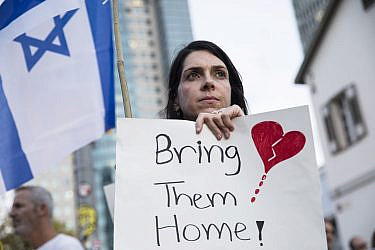 אישה מחזיקה שלט במחאה להחזרת החטופים | צילום:  Amir Levy/Getty Images