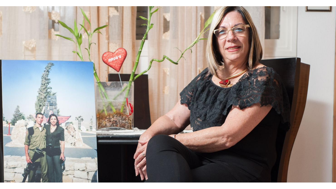 "לומדת לראות את ה'יש' מול החור הגדול שנפער, מול ה'אין' הגדול". אורה לפר מינץ ליד תמונתו של בנה, סמ"ר רז מינץ ז"ל | צילום: באדיבות המשפחה "לומדת לראות את ה'יש' מול החור הגדול שנפער, מול ה'אין' הגדול". אורה לפר מינץ ליד תמונתו של בנה, סמ"ר רז מינץ ז"ל | צילום: באדיבות המשפחה