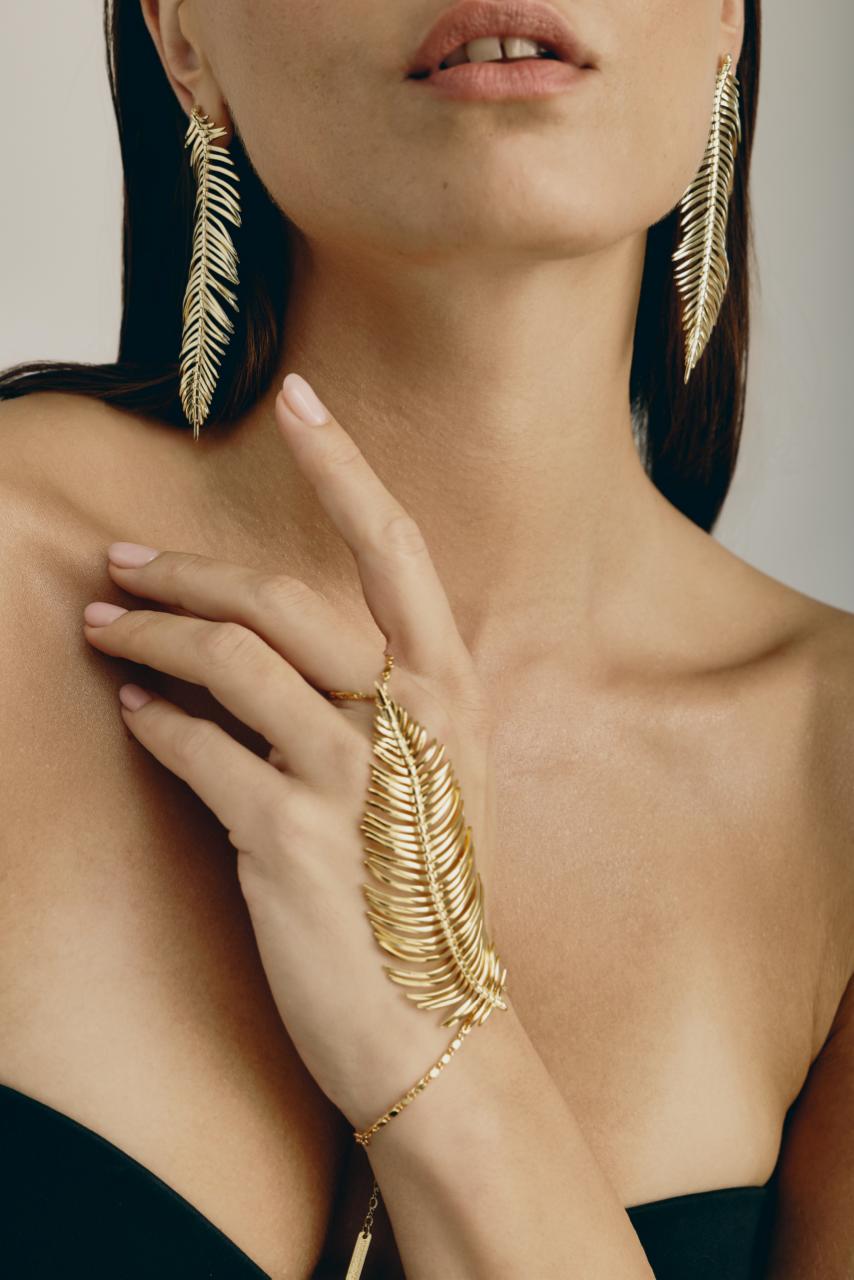 קרן וולף. צמיד טבעת נוצה בציפוי זהב 14 קראט 1,250 ש"ח, עגילי נוצה 1,450 ש"ח | צילום: שי פרנקו